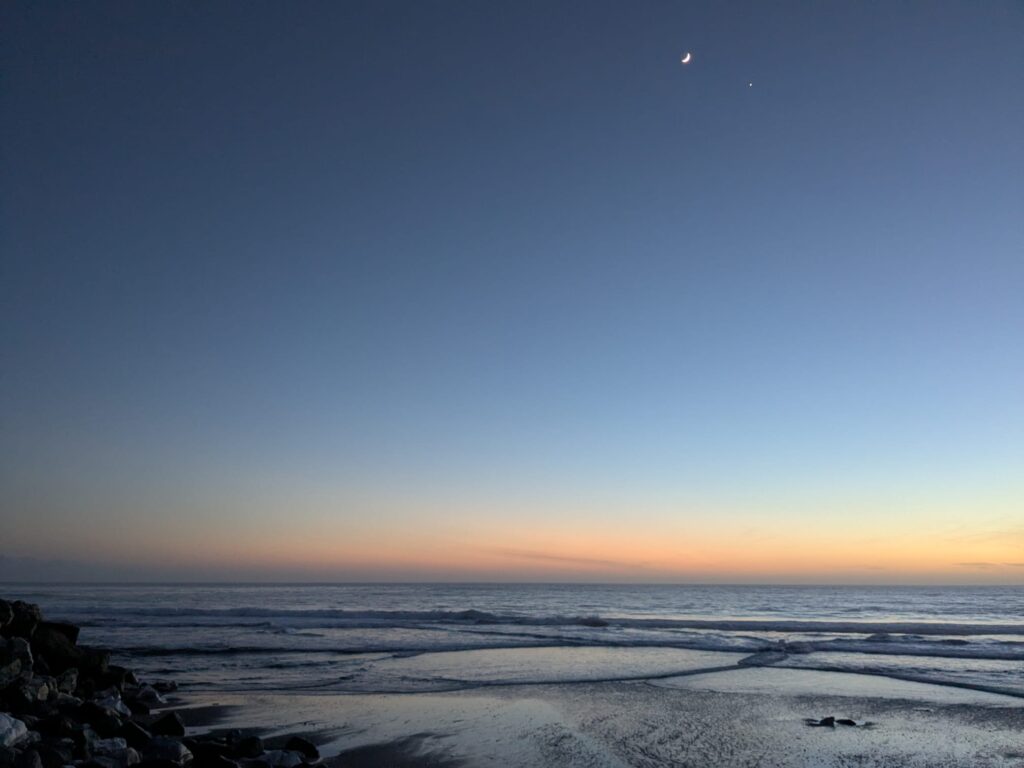 This is a picture of the ocean at dusk, with the moon and the planet Venus in the sky. Its purpose is to show some of the colors of dusk which the somatic coach likes, and offer the reader a pause for reflection with an aesthetically pleasing image.
