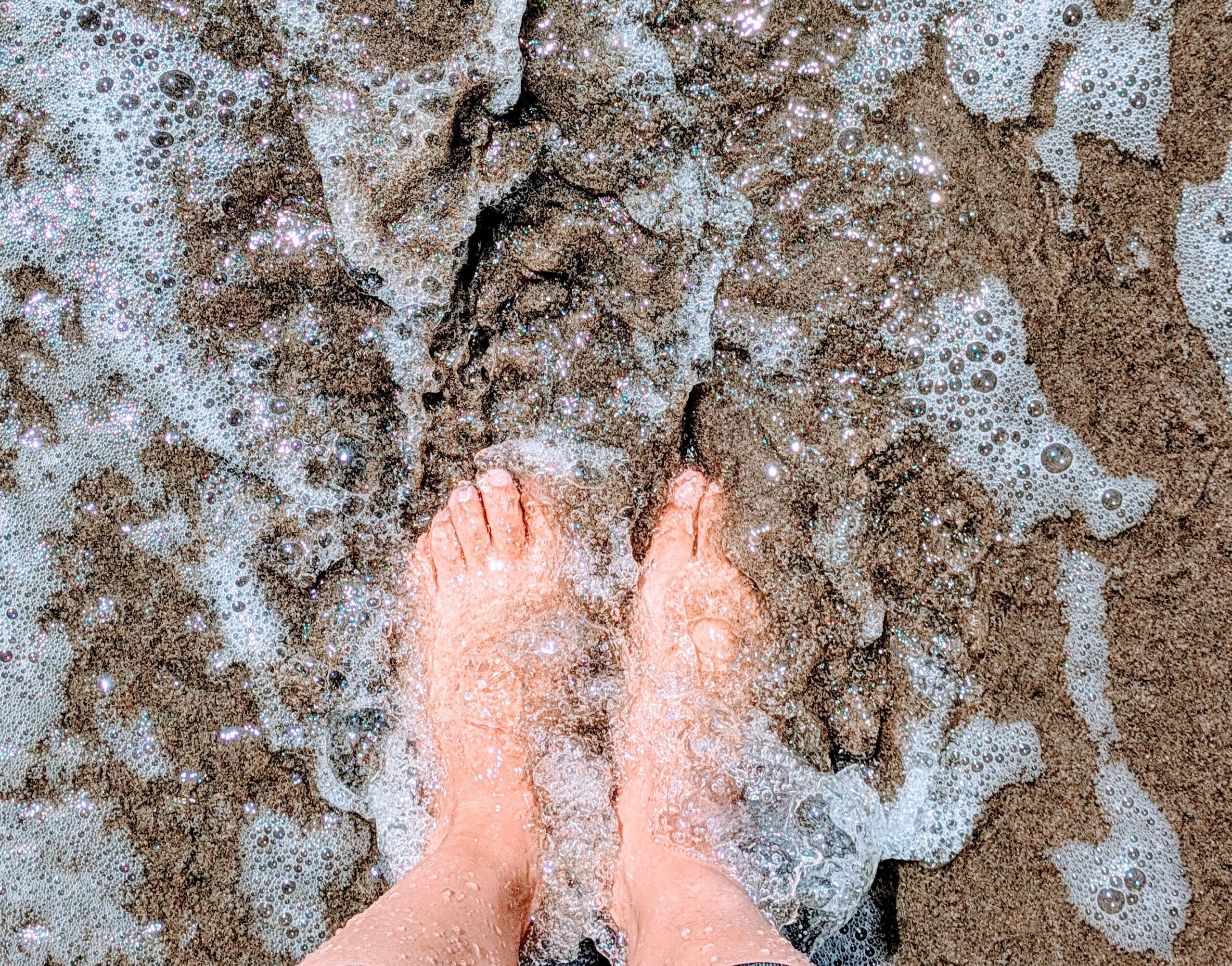 An image of feet and toes dipping into a wave from an ocean shore break. Its purpose is to mimic the experience of a single coaching session: just dipping a toe, or part of the body, into water.
