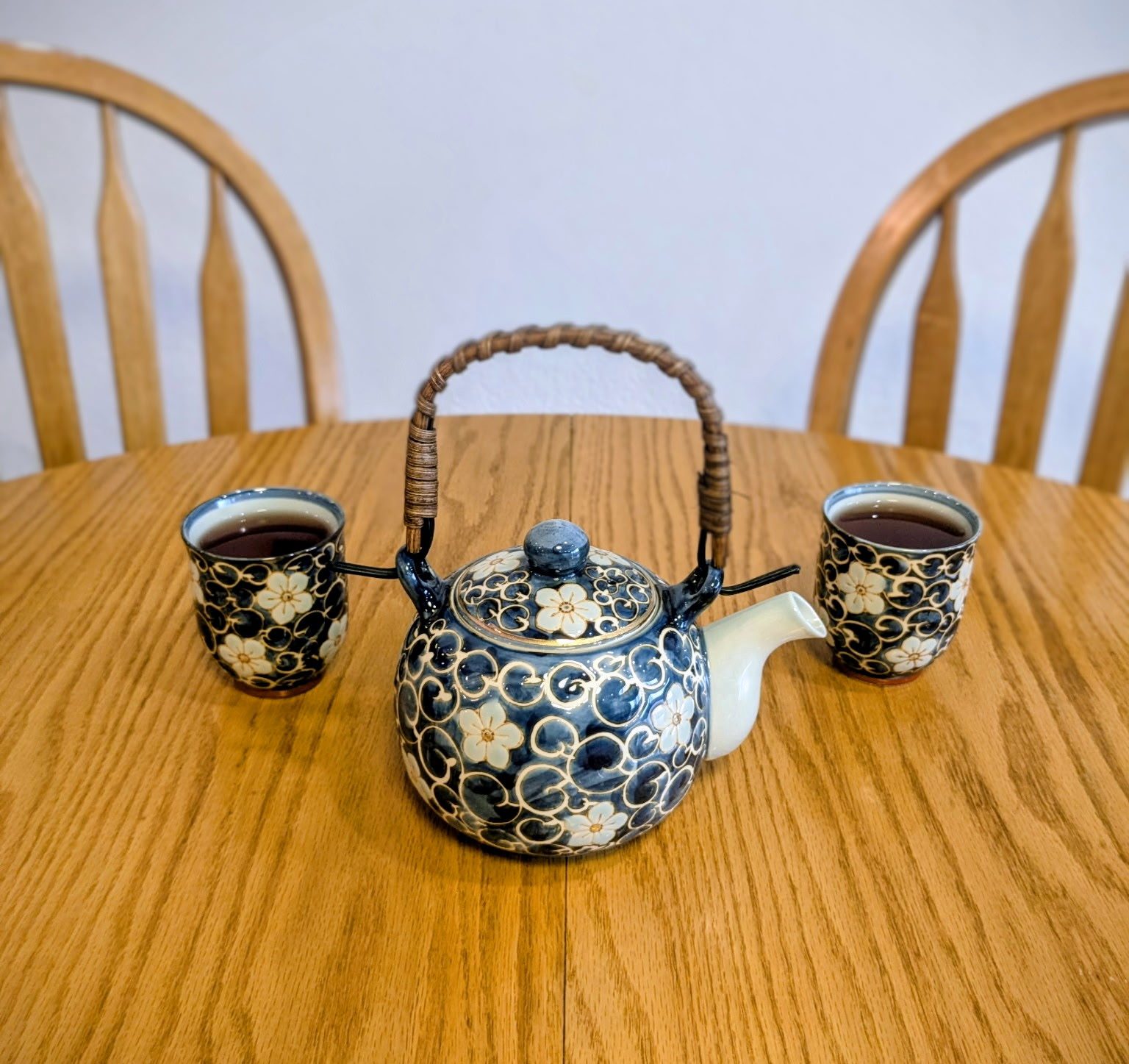 This is a photograph of two teacups at a table with two empty seats at the table. Its purpose is to provide the reader with an aesthetically pleasing image that might help them get a feel for the casual and comfortable environment they could experience in somatic coaching sessions. Copyright 2026 by Stephen Peterson, photographer